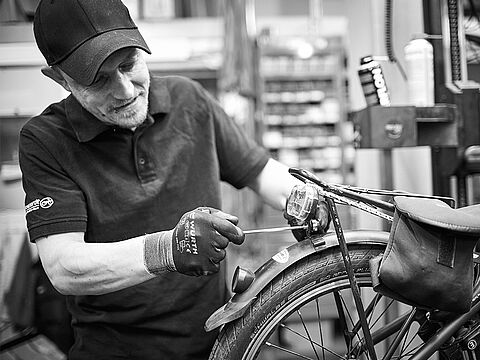 Mitarbeiter der Fahrradwerkstatt schraubt an einem Fahrrad